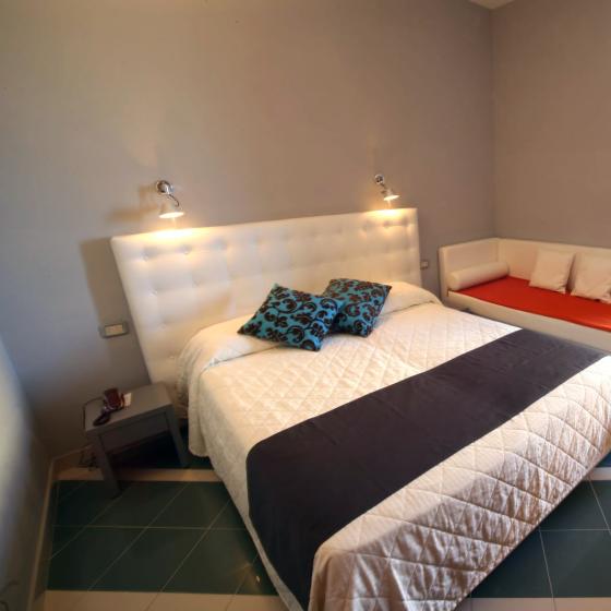 Camera moderna con letto matrimoniale, divano letto e arredamento minimalista.