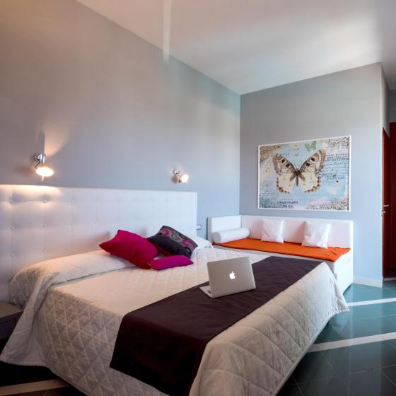 Camera moderna con letto matrimoniale, decorazioni colorate e scrivania con laptop.