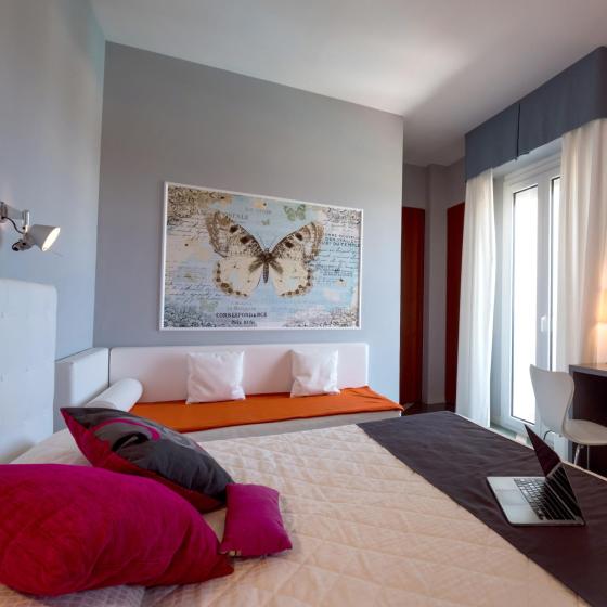 Camera moderna con letto, scrivania, TV e grande quadro di farfalla.