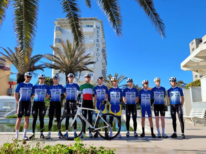 Ciclisti in divisa blu, pronti per una gara sotto il cielo azzurro.