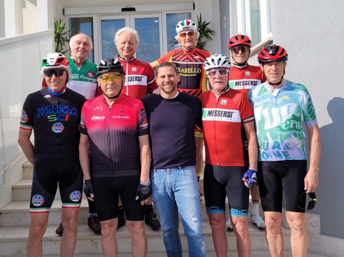 Lächelnde Radfahrergruppe vor einem Hotel, Atmosphäre von Freundschaft und Vitalität.